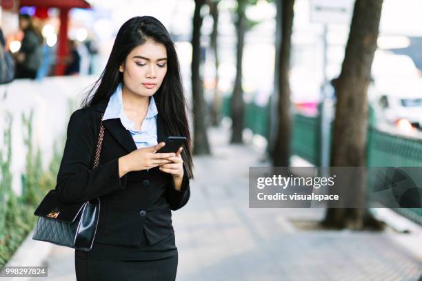 jovem mulher asiática em pé no meio da rua, olhando para ela - vanguardians - fotografias e filmes do acervo