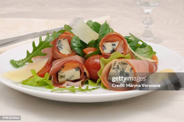 rolls of jamon with blue cheese in lettuce leaves and parmesan - jamon stockfoto's en -beelden