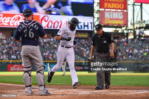 Charlie Blackmon of the Colorado Rockies touches home plate after hitting a first inning solo homerun against the Seattle Mariners at Coors Field on...