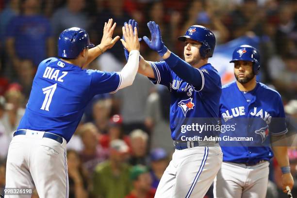 Justin Smoak high fives Aledmys Diaz of the Toronto Blue Jays after hitting a two-run home run in the ninth inning of a game against the Boston Red...