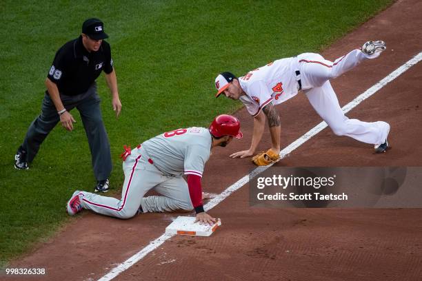 Kevin Gausman of the Baltimore Orioles goes airborne while trying to tag Jorge Alfaro of the Philadelphia Phillies during the third inning at Oriole...