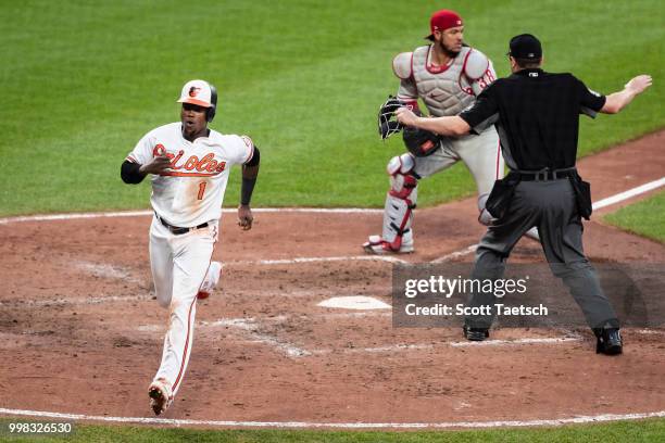 Tim Beckham of the Baltimore Orioles scores in front of Jorge Alfaro of the Philadelphia Phillies and umpire Lance Barrett during the sixth inning at...