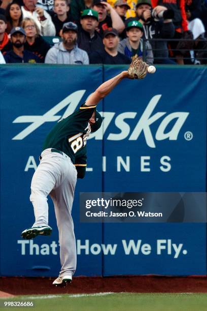 Chad Pinder of the Oakland Athletics leaps for but is unable to catch a foul ball hit off the bat of Steven Duggar of the San Francisco Giants during...