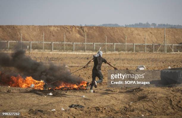 Palestinian protester seen pulling a burning tire during protests at the Gaza Strip border by Palestinian citizens that resulted in clashes between...