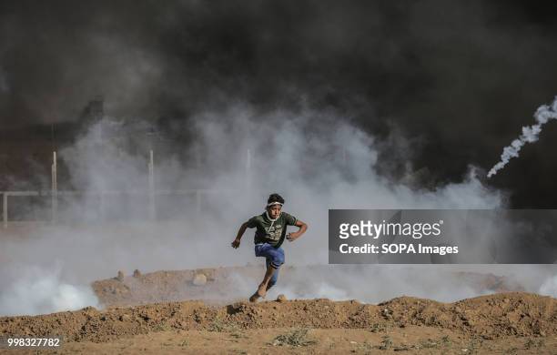Palestinian youth is seen running away from teargas canisters fired by Israeli troops during protests at the Gaza Strip border by Palestinian...
