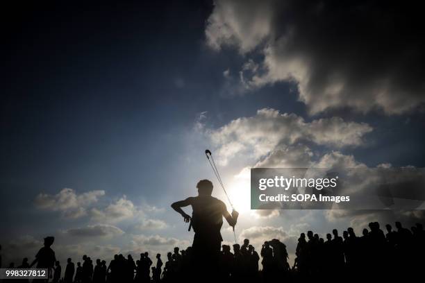 Palestinian protester seen throwing back stones at the Israeli forces during protests at the Gaza Strip border by Palestinian citizens that resulted...