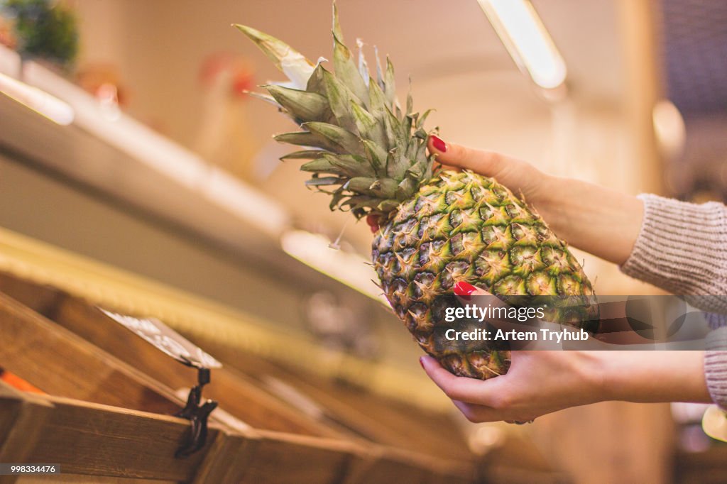 Girl with exotic pineapple in hands at supermarket