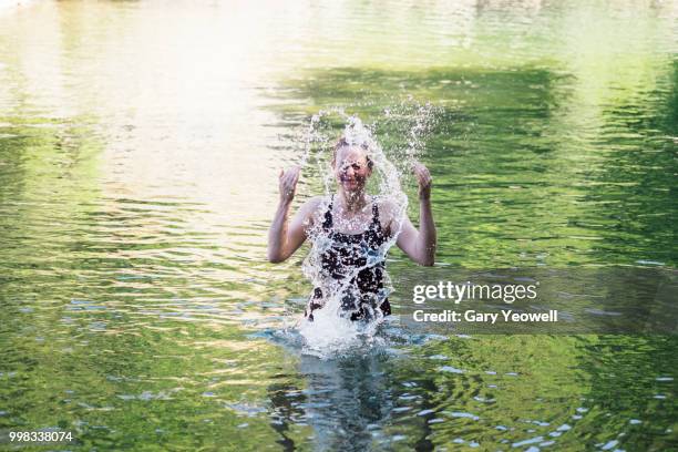 woman splashing water in a secluded lake - yeowell imagens e fotografias de stock