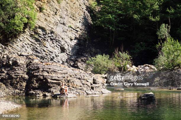 woman sitting by waters edge in a secluded lake - yeowell imagens e fotografias de stock