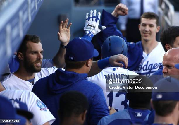 Max Muncy of the Los Angeles Dodgers is congratulated with a high-five by teammate Chris Taylor in the dugout after Muncy hit a solo homerun in the...