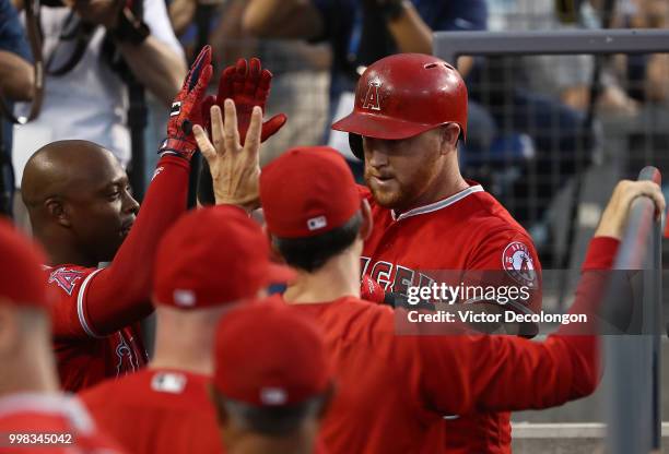 Kole Calhoun of the Los Angeles Angels of Anaheim celebrates with teammate Justin Upton in the dugout after hitting a solo homerun in the third...