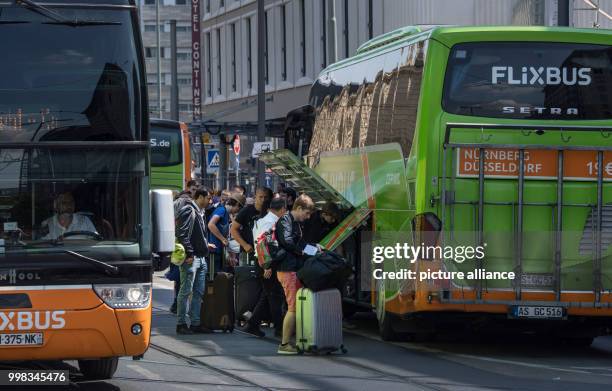 July 2018, Germany, Frankfurt: Passengers loading their luggage into a compartment of the bus in the middle of the street. There are constant chaotic...