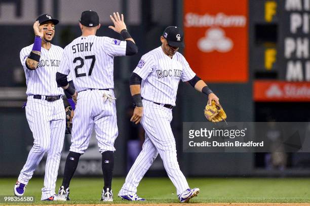 Carlos Gonzalez, Trevor Story and Gerardo Parra of the Colorado Rockies celebrate after a 10-7 win over the Seattle Mariners at Coors Field on July...