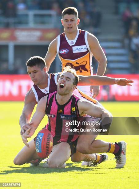Tom Mitchell of the Hawks is tackled by Jake Barrett of the Lions during the round 17 AFL match between the Hawthorn Hawks and the Brisbane Lions at...