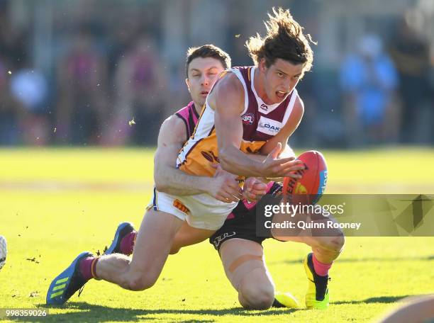 Jarrod Berry of the Lions handballs whilst being tackled by Liam Shiels of the Hawks during the round 17 AFL match between the Hawthorn Hawks and the...