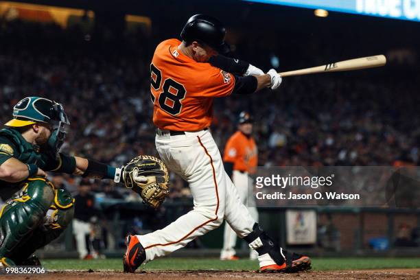 Buster Posey of the San Francisco Giants hits an RBI single against the Oakland Athletics during the sixth inning at AT&T Park on July 13, 2018 in...