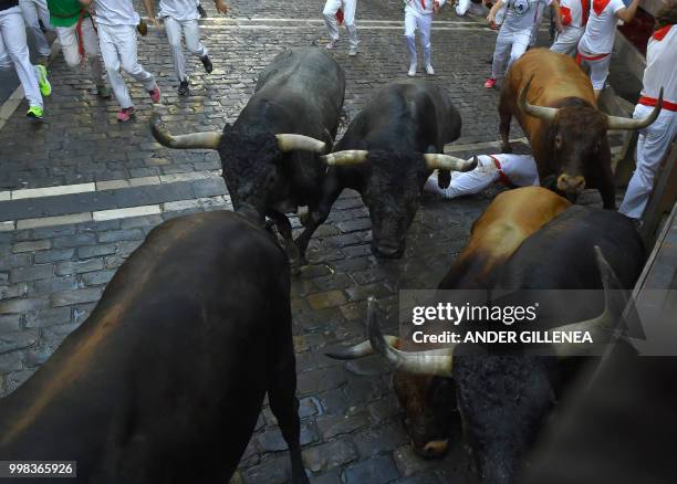 Miura fighting bulls fall during the last bullrun of the San Fermin festival in Pamplona, northern Spain on July 14, 2018. - Each day at 8am hundreds...