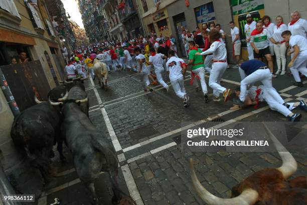 Participants run next to Miura fighting bulls on the last bullrun of the San Fermin festival in Pamplona, northern Spain on July 14, 2018. - Each day...