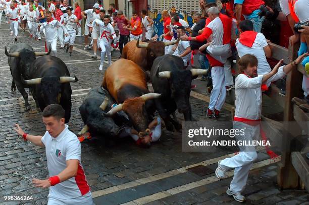 Miura fighting bulls run over a reveller on the last bullrun of the San Fermin festival in Pamplona, northern Spain on July 14, 2018. - Each day at...