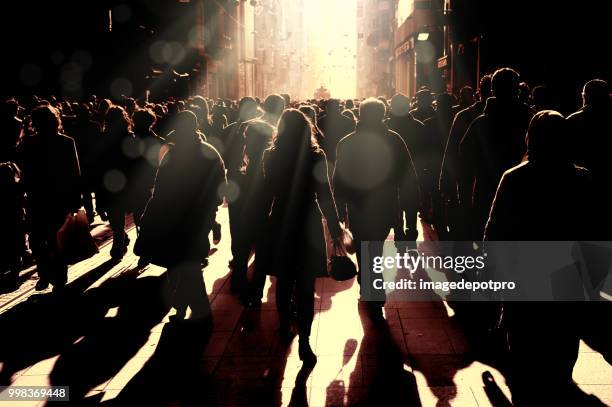 un grande gruppo di persone sagome che camminano sulla strada trafficata - crowd walking foto e immagini stock