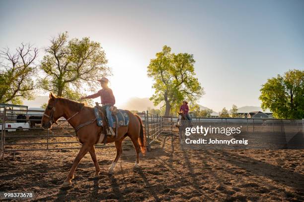 zwei junge cowgirls reiten auf dem pferd im feld - johnny greig stock-fotos und bilder