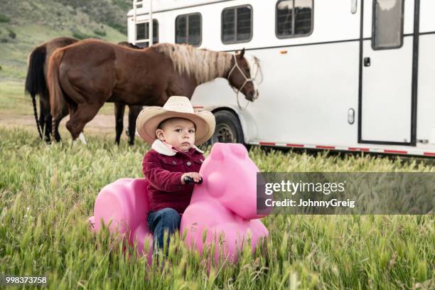 ernsthafte kleinkind cowgirl auf rosa spielzeugpferd - johnny greig stock-fotos und bilder