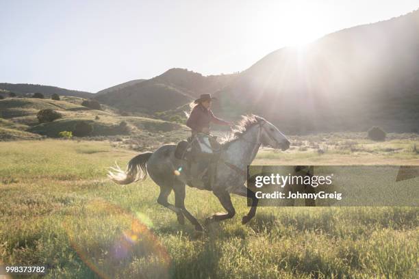 vaquera galopando a caballo en valle de utah usa - johnny greig fotografías e imágenes de stock