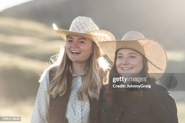 zwei junge cowgirls lächelnd nebeneinander - johnny greig stock-fotos und bilder