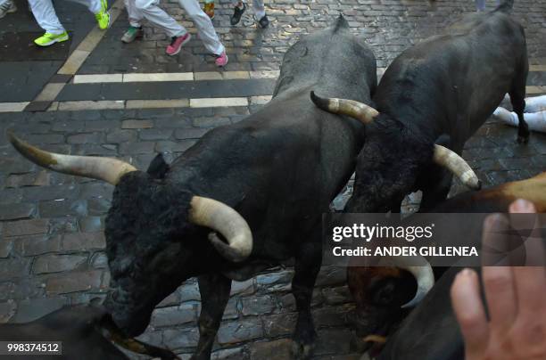 Miura fighting bulls run during the last bullrun of the San Fermin festival in Pamplona, northern Spain on July 14, 2018. - Each day at 8am hundreds...