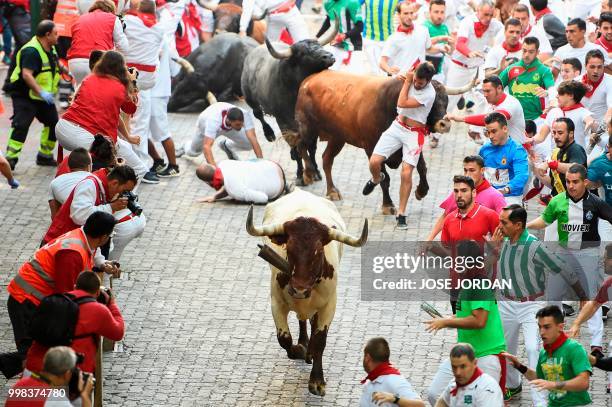 Participants run next to Miura fighting bulls on the last bullrun of the San Fermin festival in Pamplona, northern Spain on July 14, 2018. - Each day...