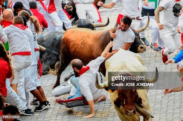 Participants fall next to Miura fighting bulls on the last bullrun of the San Fermin festival in Pamplona, northern Spain on July 14, 2018. - Each...