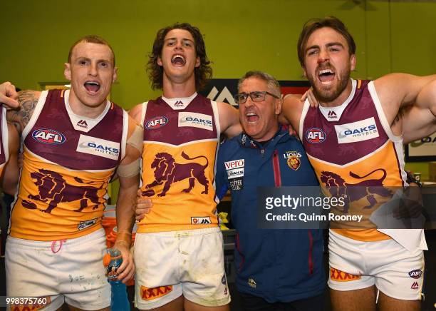 Mitch Robinson, Jarrod Berry, Lions head coach Chris Fagan and Rhys Mathieson of the Lions sing the song in the rooms after winning the round 17 AFL...