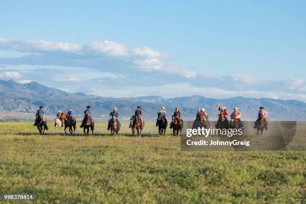 group of cowboys and cowgirls riding across open plain - mountain range stock pictures, royalty-free photos & images