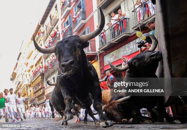 Miura fighting bulls fall on the last bullrun of the San Fermin festival in Pamplona, northern Spain on July 14, 2018. - Each day at 8am hundreds of...