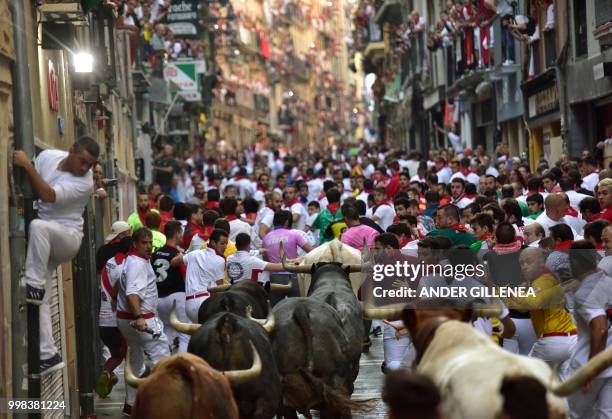 Participants run next to Miura fighting bulls on the last bullrun of the San Fermin festival in Pamplona, northern Spain on July 14, 2018. - Each day...