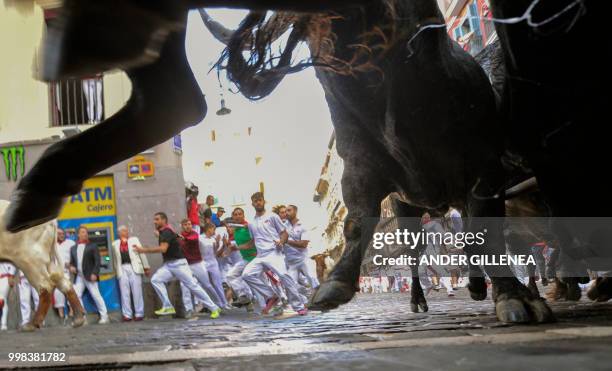 Participants run next to Miura fighting bulls on the last bullrun of the San Fermin festival in Pamplona, northern Spain on July 14, 2018. - Each day...