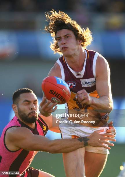 Jarrod Berry of the Lions handballs whilst being tackled by Jarman Impey of the Hawks during the round 17 AFL match between the Hawthorn Hawks and...