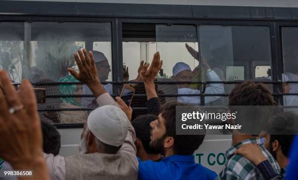 Kashmiri Muslim hajj pilgrims wave from inside a bus towards their relatives as they depart for the annual Hajj pilgrimage to Mecca on July 14, 2018...