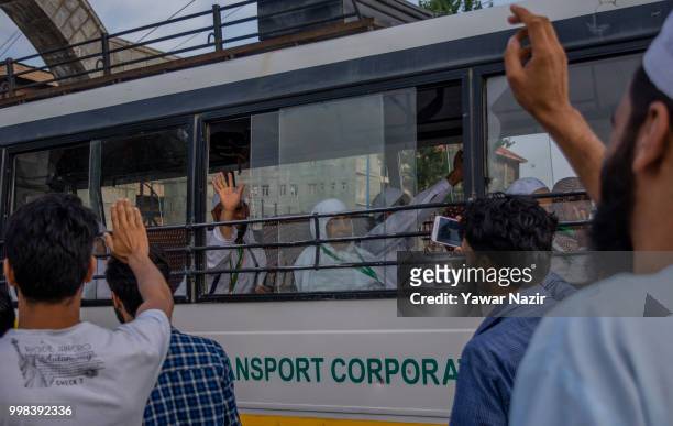 Kashmiri Muslim hajj pilgrims wave from inside a bus towards their relatives as they depart for the annual Hajj pilgrimage to Mecca on July 14, 2018...