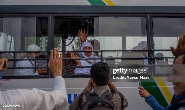 Kashmiri Muslim hajj pilgrims wave from inside a bus towards their relatives as they depart for the annual Hajj pilgrimage to Mecca on July 14, 2018...