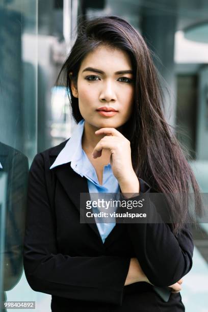 一個年輕的亞洲婦女靠在玻璃牆上的肖像。 - vanguardians 個照片及圖片檔