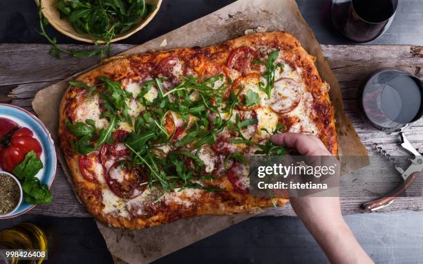 preparing gourmet pizza, close-up of hand topping pizza with arugula - zelfgemaakt stockfoto's en -beelden