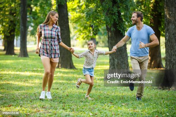 spielerische familie im park ausgeführt werden, während die hand in hand - emir memedovski stock-fotos und bilder