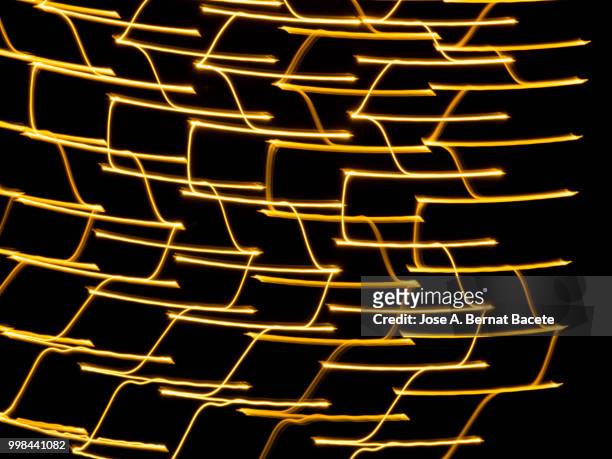 close-up abstract pattern of intertwined colorful light beams of colors yellow and gol colored on a  black background. - gol stock pictures, royalty-free photos & images