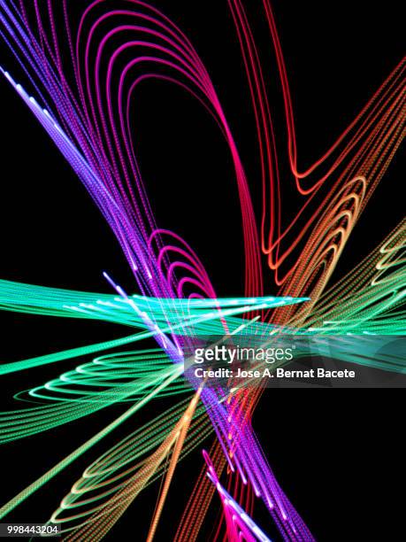 close-up abstract pattern of intertwined colorful light beams of color blue, green and pink on a  black background. - bernat photos et images de collection