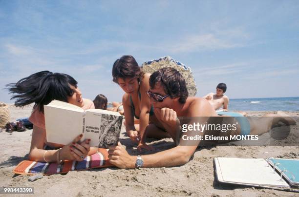 Vacanciers lisant sur la plage en 1976 à Montpellier, France.