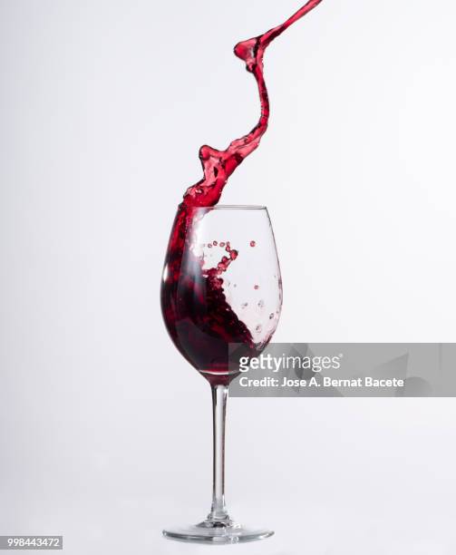 red wine splashing in glass in front of white background - bernat bacete imagens e fotografias de stock