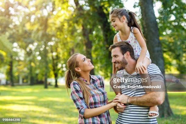 junge liebevolle familie mit spaß im park - emir memedovski stock-fotos und bilder