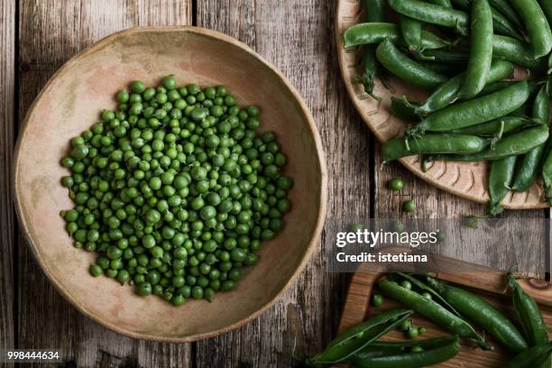 young fresh green peas on wooden table - peas stockfoto's en -beelden