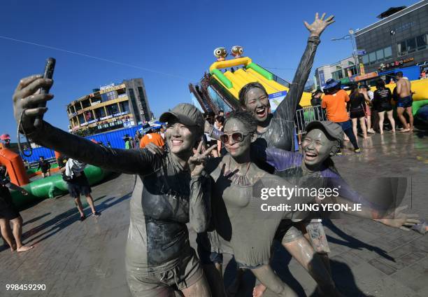 Tourists covered with mud pose for a selfie during the 21th Boryeong Mud Festival at Daecheon beach in Boryeong on July 14, 2018. - The annual...